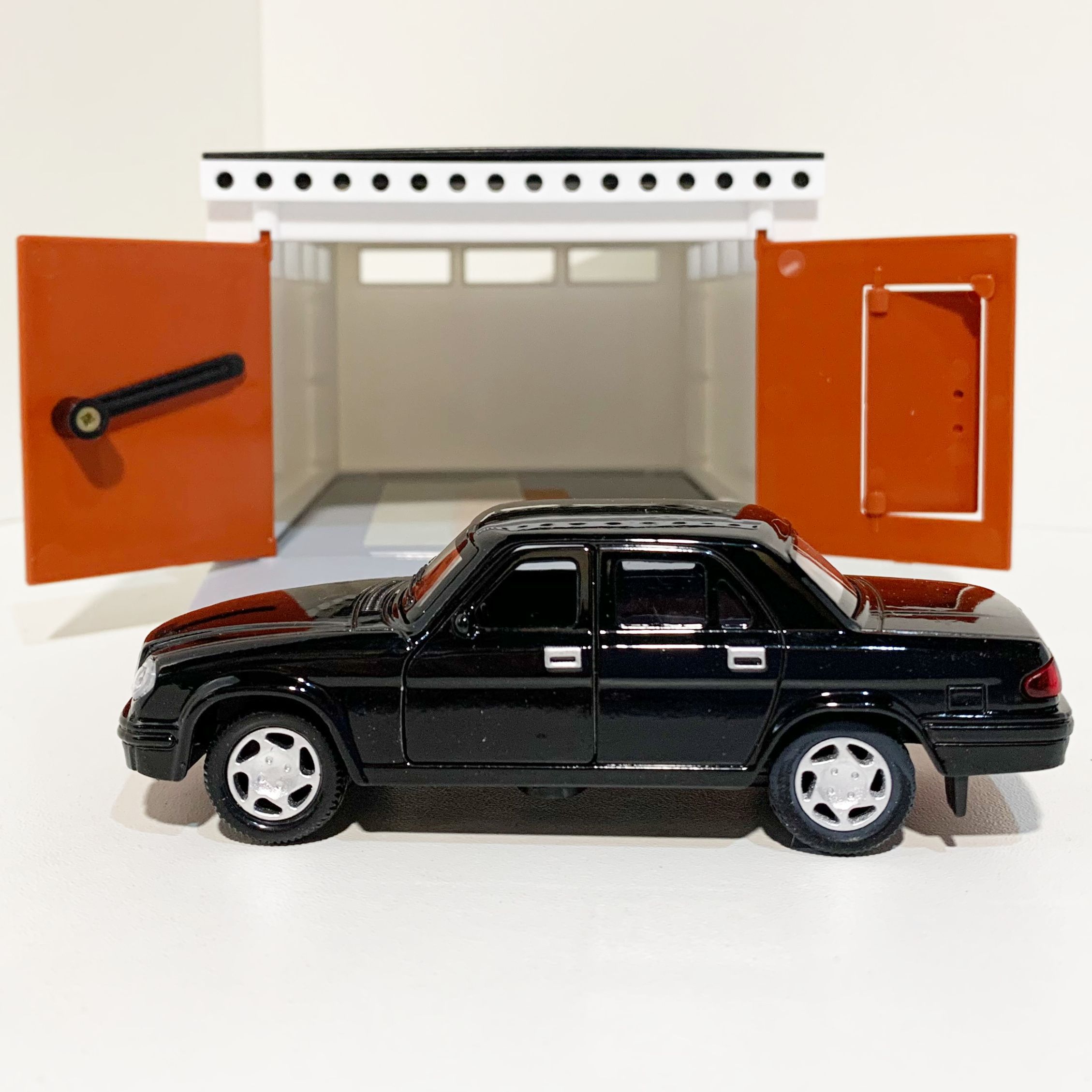 Гараж с распашными воротами и металлическая инерционная машинка Волга 3110 с 2-мя открывающимися дверями 12 см - черная